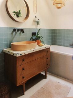 a bathroom with a sink, mirror and bathtub next to a rug on the floor