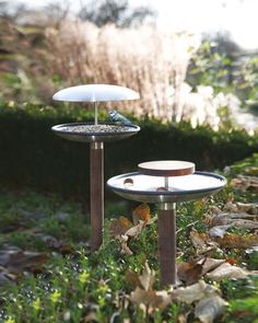 two bird feeders sitting on top of each other in the middle of some grass