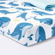 a blue and white bed sheet with whale print on the bottom, next to a pillow