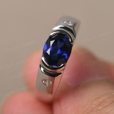 a person holding a ring with a blue stone in it