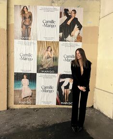 a woman standing in front of a wall with posters on it