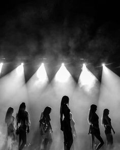 a group of women standing on top of a stage in front of bright spotlights