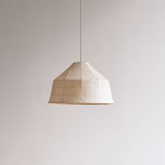 a white lamp hanging from a ceiling with a light brown shade on it's side