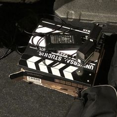 a black and white photo of a movie clapper sitting on the ground next to a pair of headphones