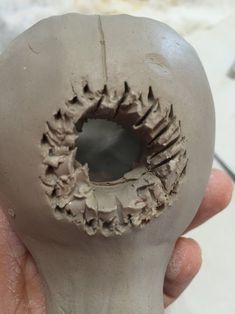 a person holding a clay object with holes in it's center and the inside of its mouth