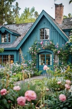 a blue house with lots of flowers around it