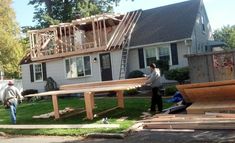 two men are working on the roof of a house that's being built with wooden boards