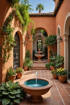 an outdoor courtyard with a fountain and potted plants on either side of the walkway