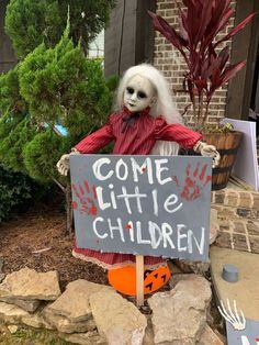 a creepy doll sitting on top of a sign in front of a house that says come little children