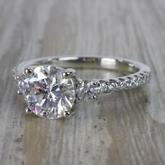 an engagement ring with two round diamonds on the side and pave - set shoulders