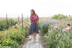 a woman standing in the middle of a flower garden