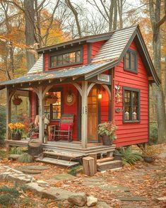 a small red cabin in the woods surrounded by fall leaves and trees with lots of foliage