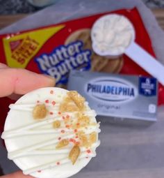 a person holding an ice cream sundae in their left hand and some other food on the table