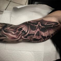 a man's arm with a skull and wings tattoo on it