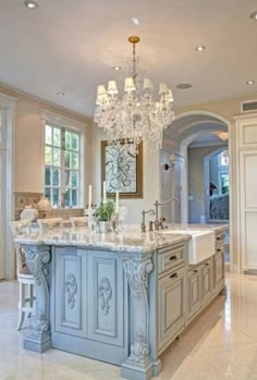 a large kitchen with an island and chandelier in the center, surrounded by marble flooring