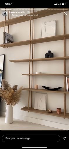 a wooden shelf with books and pictures on it in a room that has white walls