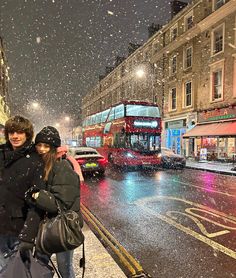 two people are standing on the sidewalk in the snow