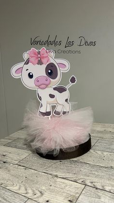 a card with a cow wearing a pink tutu on top of a wooden table