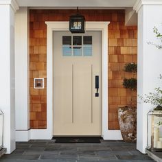 a white front door with two lanterns on each side and a light hanging above it