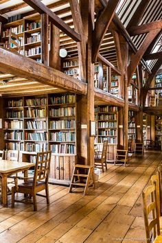 the inside of a library with wooden tables and chairs, bookshelves full of books