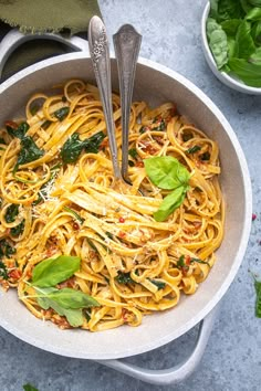 a bowl filled with pasta and spinach on top of a table