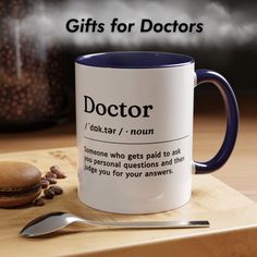 a blue and white coffee mug sitting on top of a wooden table next to a spoon