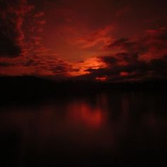 the sky is red and cloudy at night, with some clouds reflected in the water