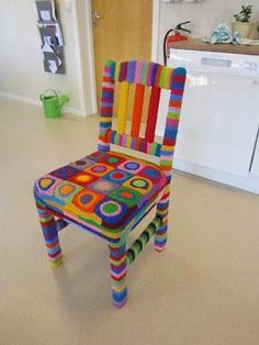 a multicolored crocheted chair sits in the middle of a kitchen floor