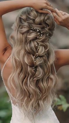 a woman with long blonde hair wearing a wedding dress and braided in pearls is looking back