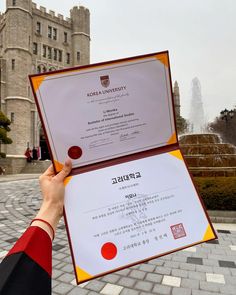 a person holding up a certificate in front of a building