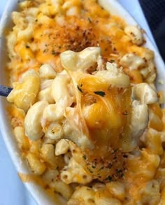 macaroni and cheese in a white bowl with a blue serving utensil