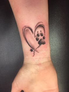 a heart shaped tattoo with paw prints on the wrist