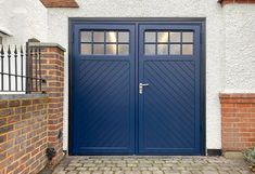 a blue double door in front of a white house with brick wall and gated entrance