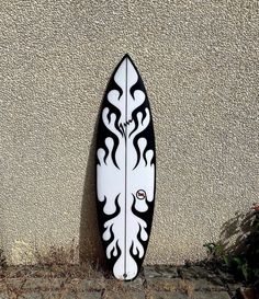 a white and black surfboard sitting against a wall