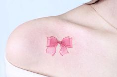 a woman's breast with a pink bow tattoo on her left shoulder and chest