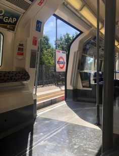 the inside of a subway car with its doors open and trees in the background,