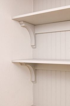 two white shelves in the corner of a room