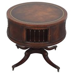 a round wooden table with metal trimmings on the top and bottom, sitting on an ornate pedestal