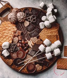 an assortment of chocolates and marshmallows on a wooden platter