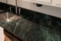 green marble counter top in a kitchen with stainless steel sink and dishwasher below