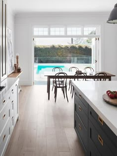 a kitchen with an island and dining table next to a swimming pool in the background