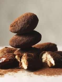 chocolate donuts stacked on top of each other with powdered sugar and nuts around them