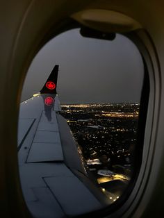 an airplane wing with the lights on at night seen from inside another plane's window