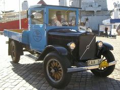 an old blue truck is parked on the street