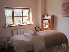 a bedroom with a bed, chair and bookcase in it's corner next to a window