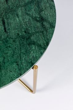 a green marble table with gold legs on a white background, showing the edge of the table