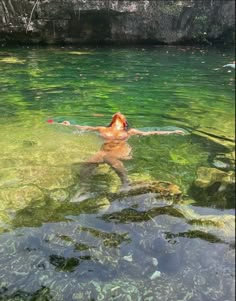 a person swimming in the water with their head above the water's surface, surrounded by algae