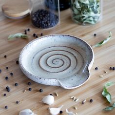 a white bowl sitting on top of a wooden table next to some spices and herbs