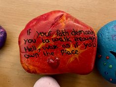 three painted rocks with writing on them sitting next to each other in front of a wooden table