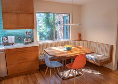 a kitchen table with two chairs and a bench in front of the window next to it